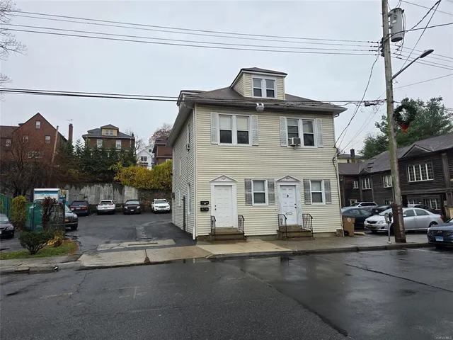 a front view of a building with cars parked on road