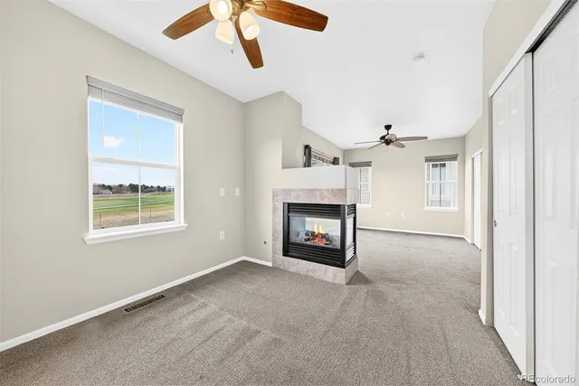 a view of an empty room with chandelier fan and fire place