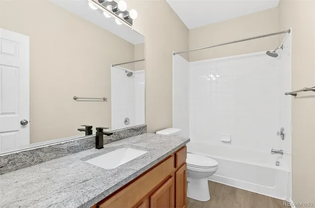 a bathroom with a granite countertop sink toilet and shower