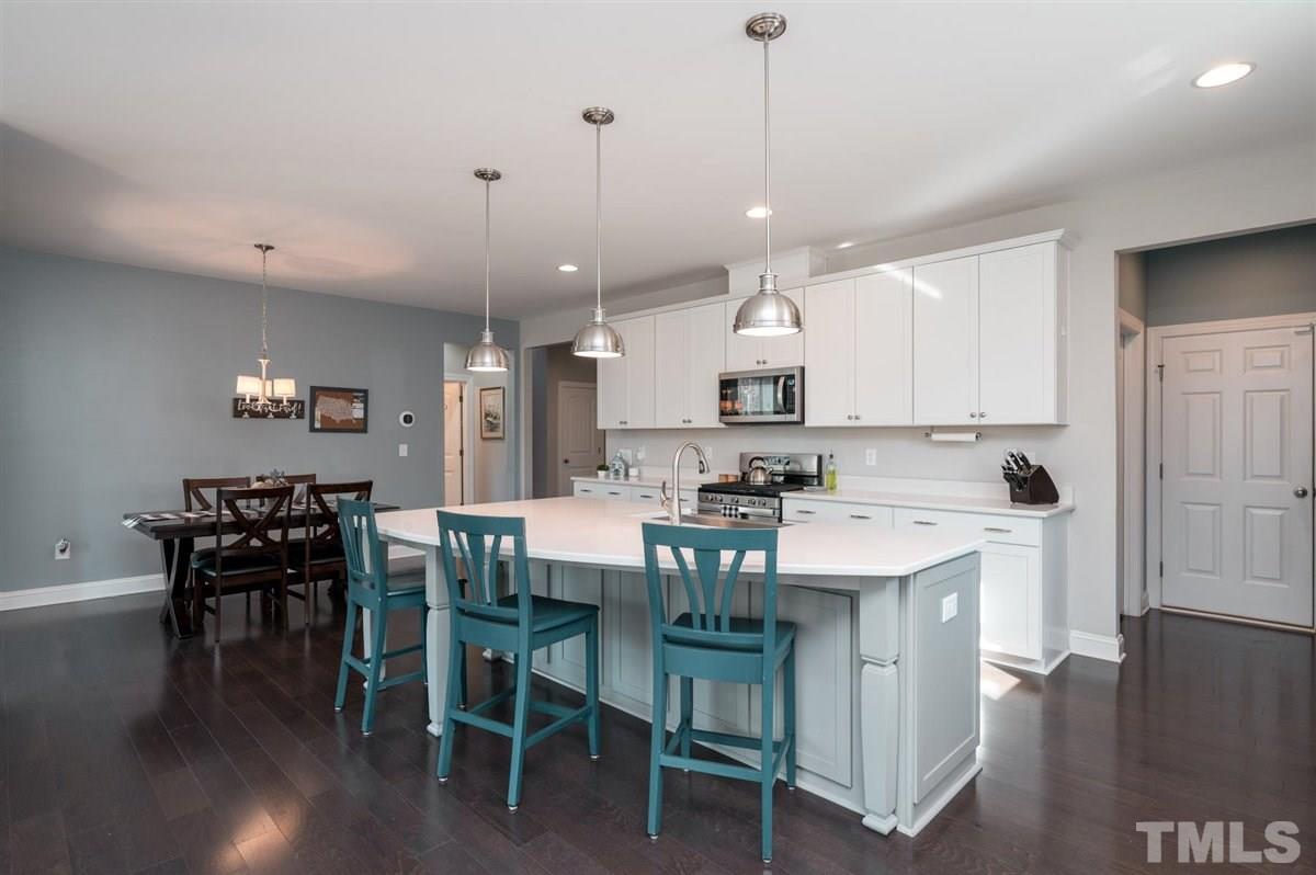 7056 Rex Road Holly Springs, NC 27540 - Photo 3 of 28 Quartz countertops, row of cabinets, deep farmhouse sink and a huge walk-in pantry makes this kitchen the heart of the home!