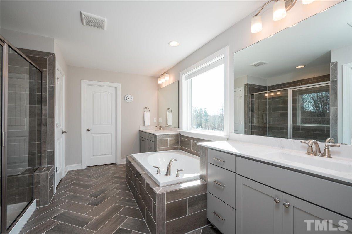 7056 Rex Road Holly Springs, NC 27540 - Photo 7 of 28 Large owner's suite with dual vanities, a large walk-in tiled shower, soaking tub and 2 closets!