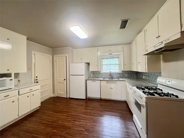 a kitchen with granite countertop a sink a counter space stainless steel appliances and cabinets