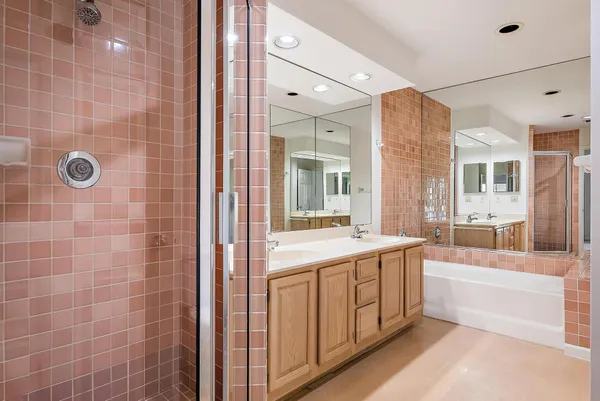 a bathroom with a tub a sink and a large mirror