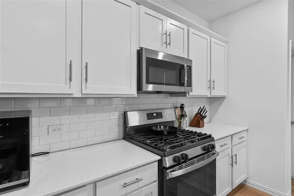 a kitchen with stainless steel appliances granite countertop white cabinets a stove top oven and granite counter tops