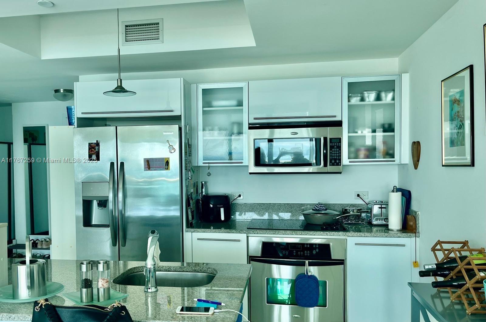 888 Biscayne Boulevard, Unit 4306 Miami, FL 33132 - Photo 23 of 70 a kitchen with stainless steel appliances kitchen island granite countertop a refrigerator a stove and a sink with wooden floor