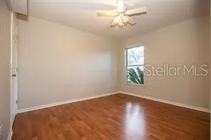 an empty room with wooden floor chandelier fan and windows