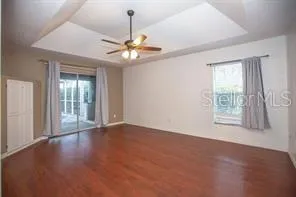a view of an empty room with chandelier fan and a window