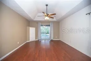 a view of an empty room with window and wooden floor