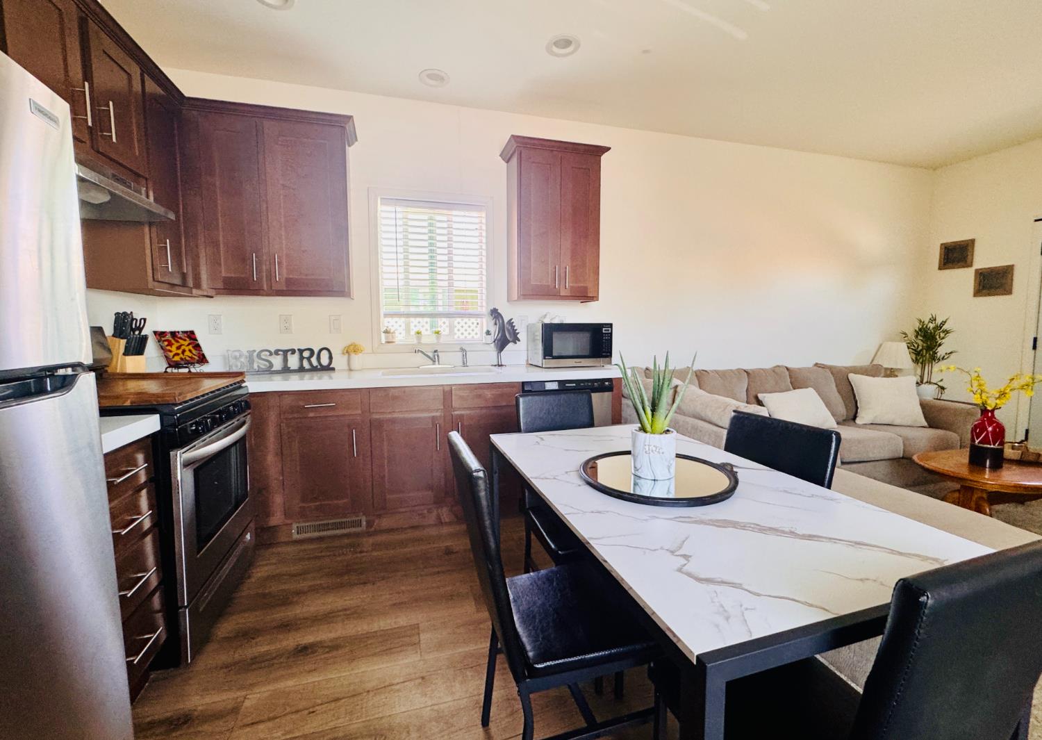 360 East Grant Line Road, Unit 16 Tracy, CA 95376 - Photo 5 of 36 Open-concept kitchen and dining area featuring rich wood cabinetry, stainless steel appliances, a white countertop, and wood-finish flooring