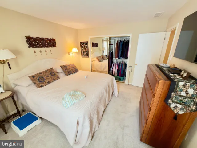 a bedroom with a bed and a flat tv screen on dresser