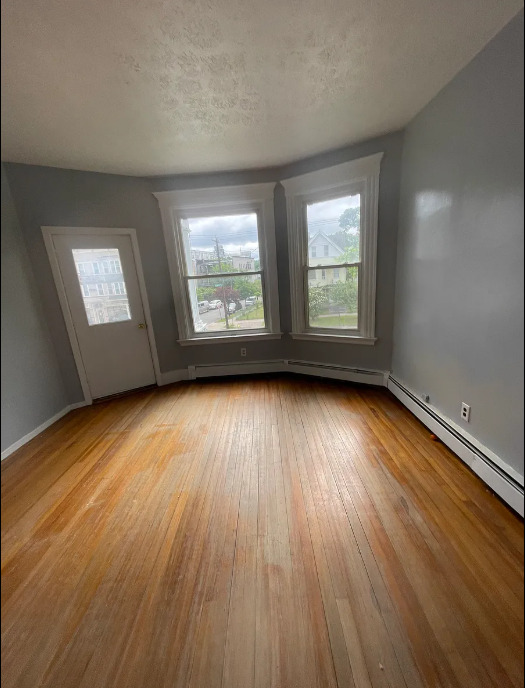 414 Dixwell Avenue, Unit 2 New Haven, CT 06511 - Photo 6 of 8 an empty room with wooden floor and windows