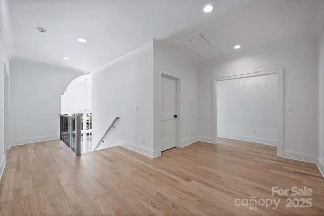 a view of an empty room with wooden floor and white walls
