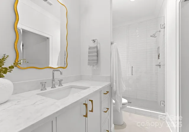 a bathroom with a granite countertop sink two mirror and shower