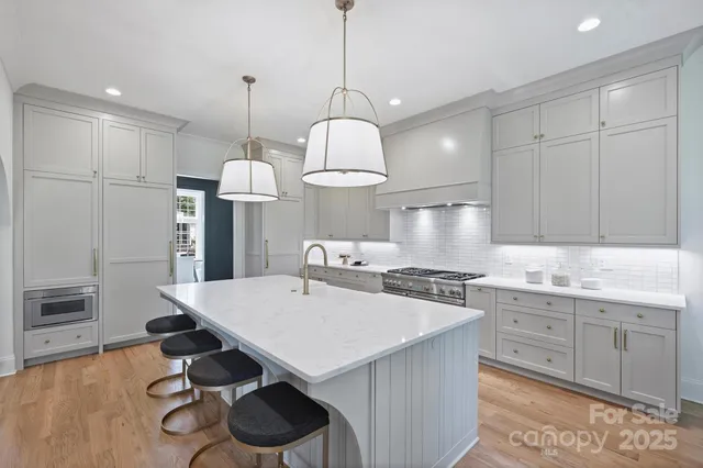 a kitchen with stainless steel appliances a stove a sink a center island and cabinets