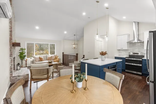 a living room with stainless steel appliances kitchen island granite countertop a table chairs and a view of living room