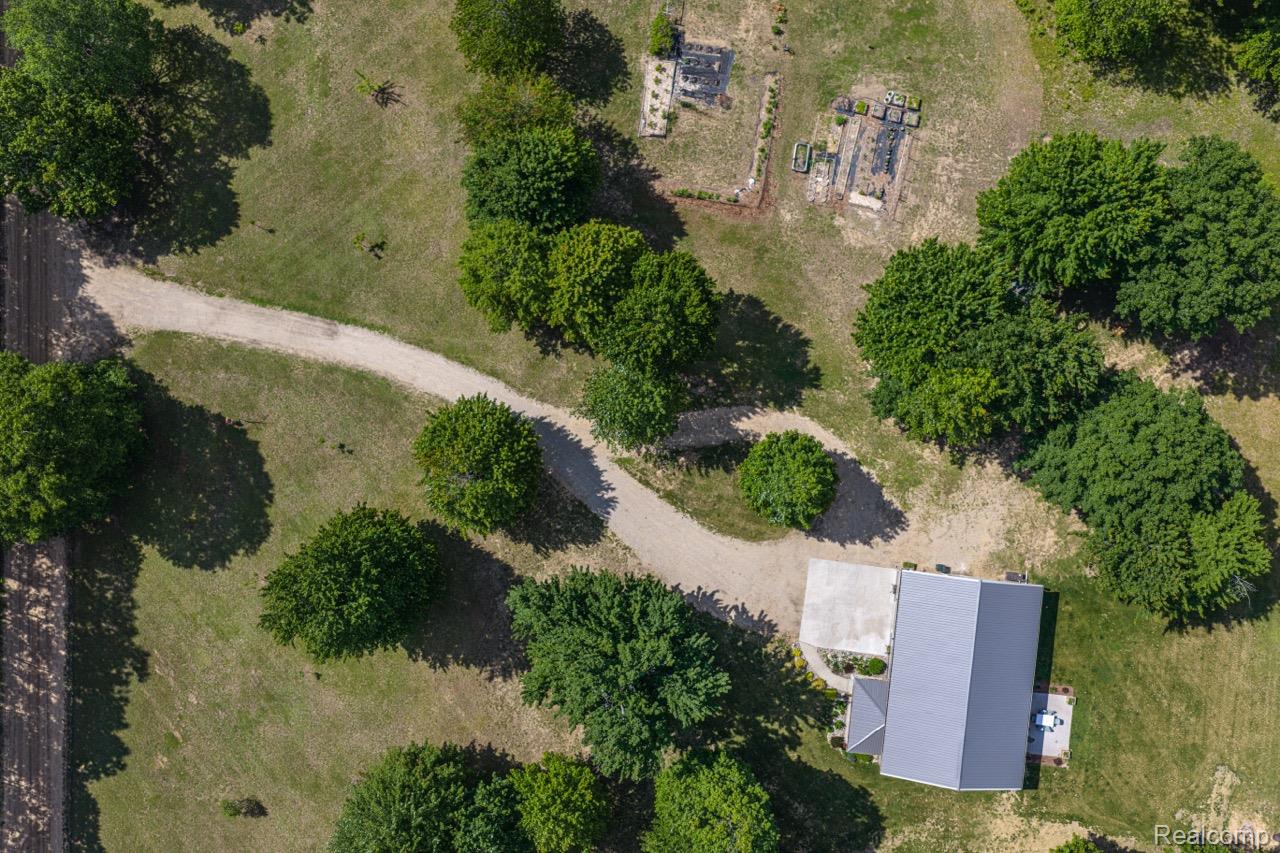 2418 South 41st Road South Cadillac, MI 49601 - Photo 22 of 57 Aerial property overview featuring a gravel driveway, mature trees, open grassy areas, and a single-story residence with a gray metal roof