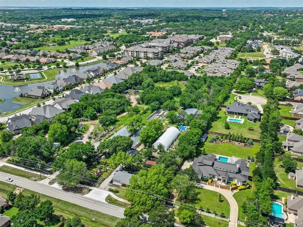 an aerial view of residential houses with outdoor space and trees