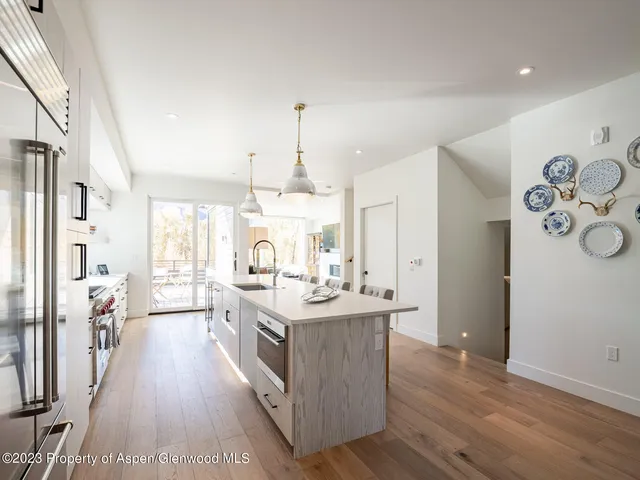 a large kitchen with stainless steel appliances a stove a sink dishwasher and a dining table with wooden floor