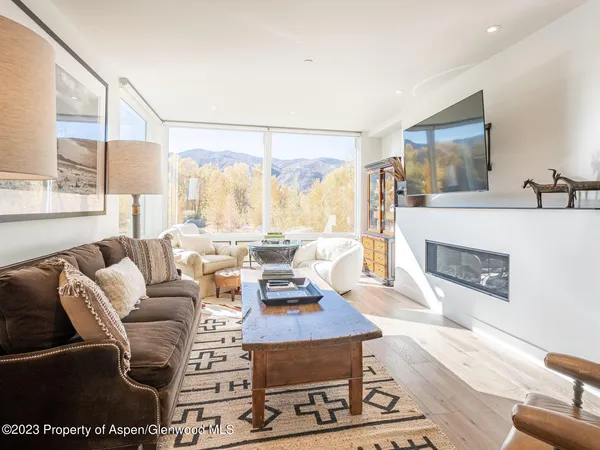 a living room with furniture a large window and a fireplace