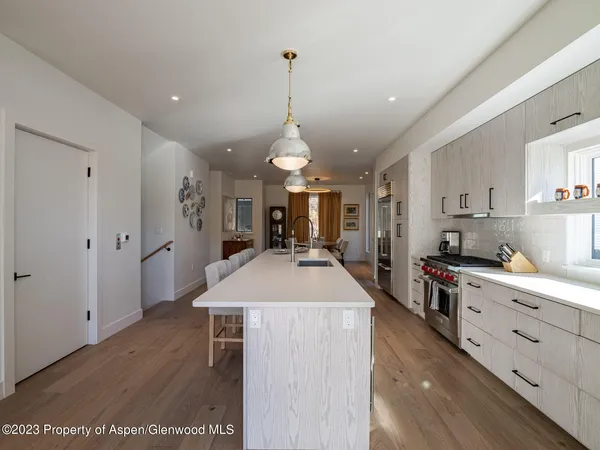 a large kitchen with kitchen island a stove a refrigerator a sink dishwasher and white cabinets with wooden floor