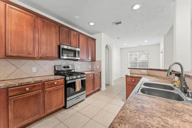 a kitchen with stainless steel appliances granite countertop a stove a sink and a microwave