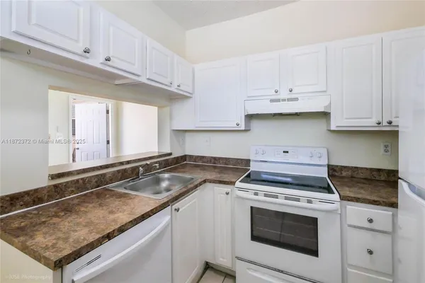 a kitchen with granite countertop a stove sink and cabinets
