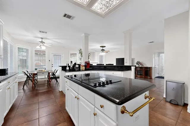 a kitchen with a stove white cabinets a dining table and chairs