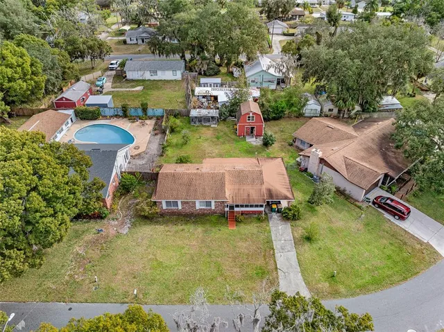 an aerial view of a house with swimming pool and large trees