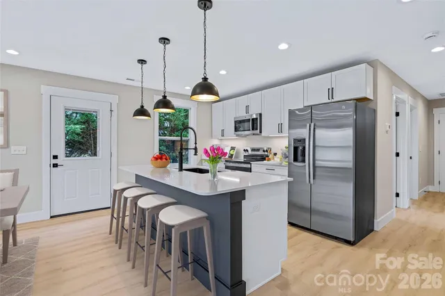 a kitchen with kitchen island white cabinets and stainless steel appliances