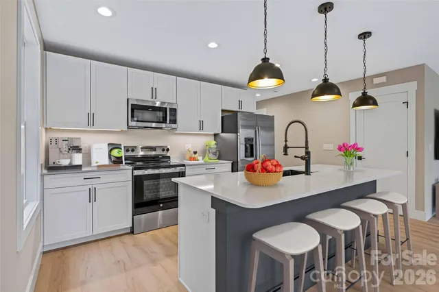 a kitchen with stainless steel appliances granite countertop a sink a stove a dining table and chairs