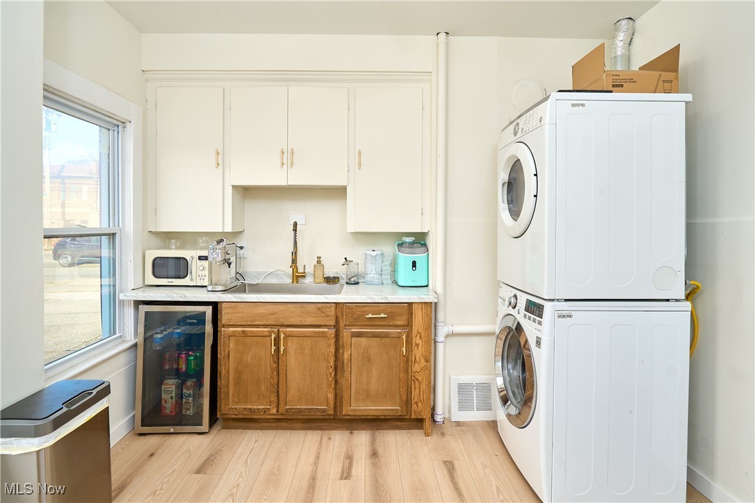 5432 State Road Parma, OH 44134 - Photo 19 of 47 Laundry room featuring light wood finished floors, beverage cooler, and stacked washer / dryer