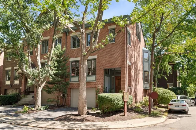 a view of a brick house with a yard and large tree