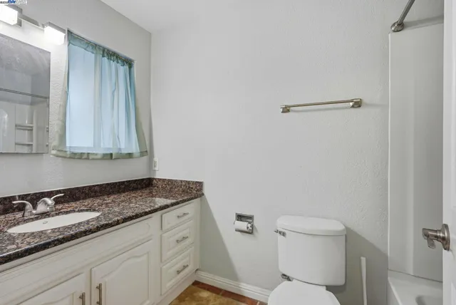 a bathroom with a granite countertop sink a toilet and with mirror