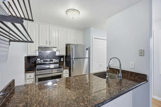 a kitchen with stainless steel appliances granite countertop a sink stove and refrigerator