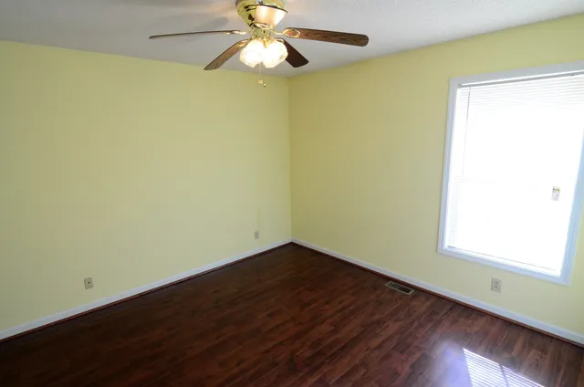 an empty room with a window and a ceiling fan