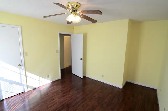 a view of a big room with wooden floor and a chandelier fan