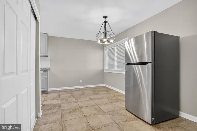 a view of a refrigerator in kitchen and white cabinets
