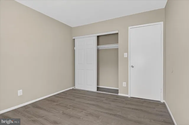 a view of an empty room with wooden floor and closet