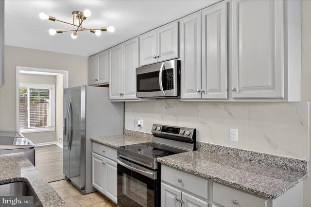 a kitchen with stainless steel appliances granite countertop a stove a microwave and a refrigerator