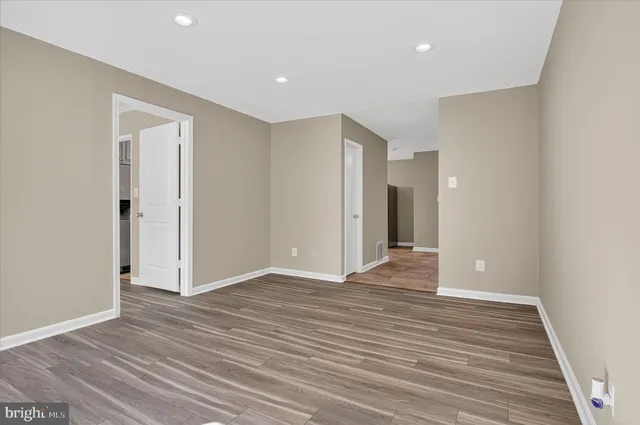 a view of an empty room with wooden floor and closet