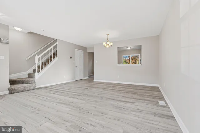 a view of an empty room with wooden floor and staircase