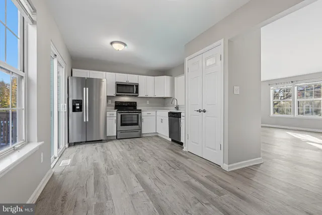 a kitchen with a refrigerator a stove top oven a sink and cabinets