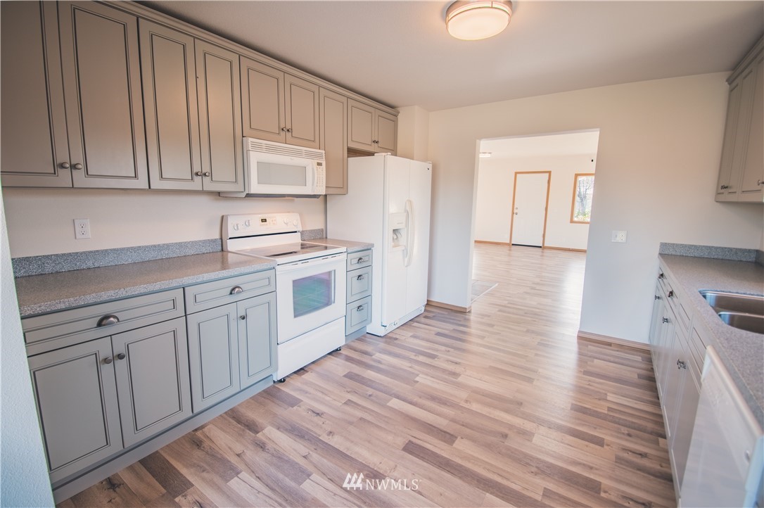 8414 183rd Avenue Southwest Rochester, WA 98579 - Photo 9 of 19 a kitchen with white cabinets and wooden floor