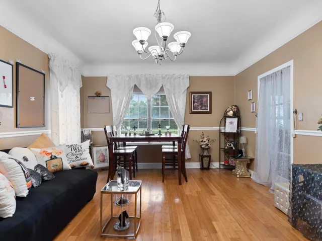 a living room with furniture dining table wooden floor and a chandelier