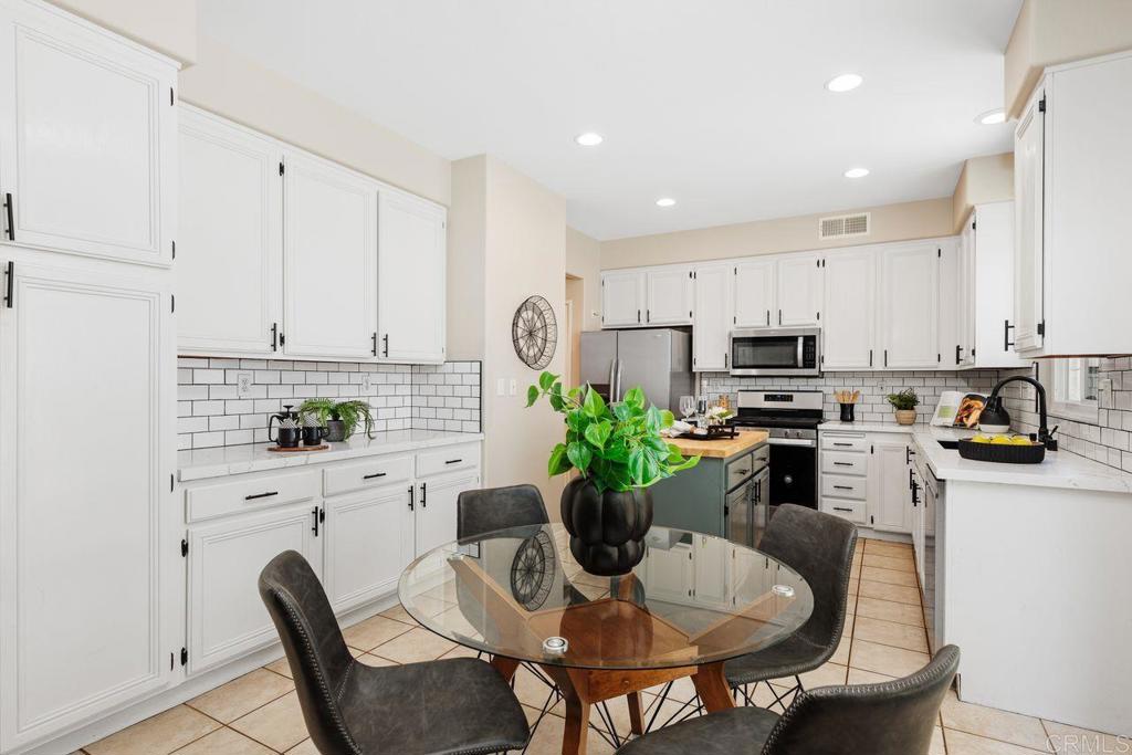 160 Belflora Way Oceanside, CA 92057 - Photo 11 of 41 a kitchen with stainless steel appliances kitchen island granite countertop a dining table chair and white cabinets