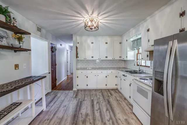 a kitchen with granite countertop a sink a window and white cabinets