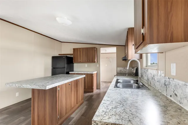 a kitchen with granite countertop a sink stove and refrigerator