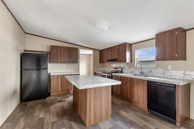 a kitchen with kitchen island granite countertop a sink stove and refrigerator