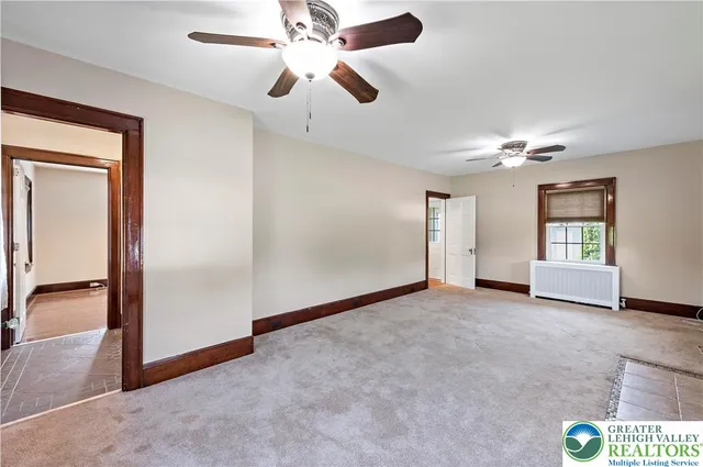 an empty room with chandelier fan and windows