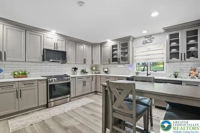 a kitchen with stainless steel appliances granite countertop a stove top oven a sink dishwasher a dining table and chairs with wooden cabinets